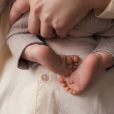 Nærbillede af babyfødder holdt af kvinde iført cremefarvet bluse