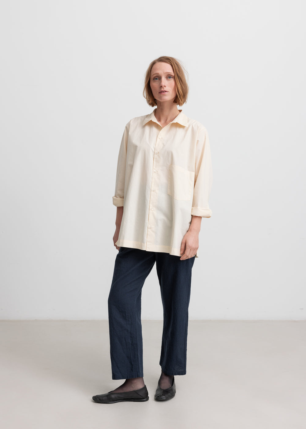 Kvinde iført cremefarvet bluse med lange ærmer og klassisk krave