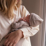 Kvinde holder baby iført cremefarvet bluse