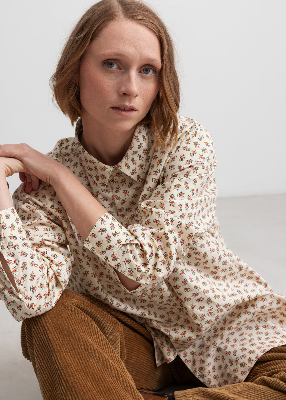Kvinde iført blomstret skjorte med knaplukning og lange ærmer