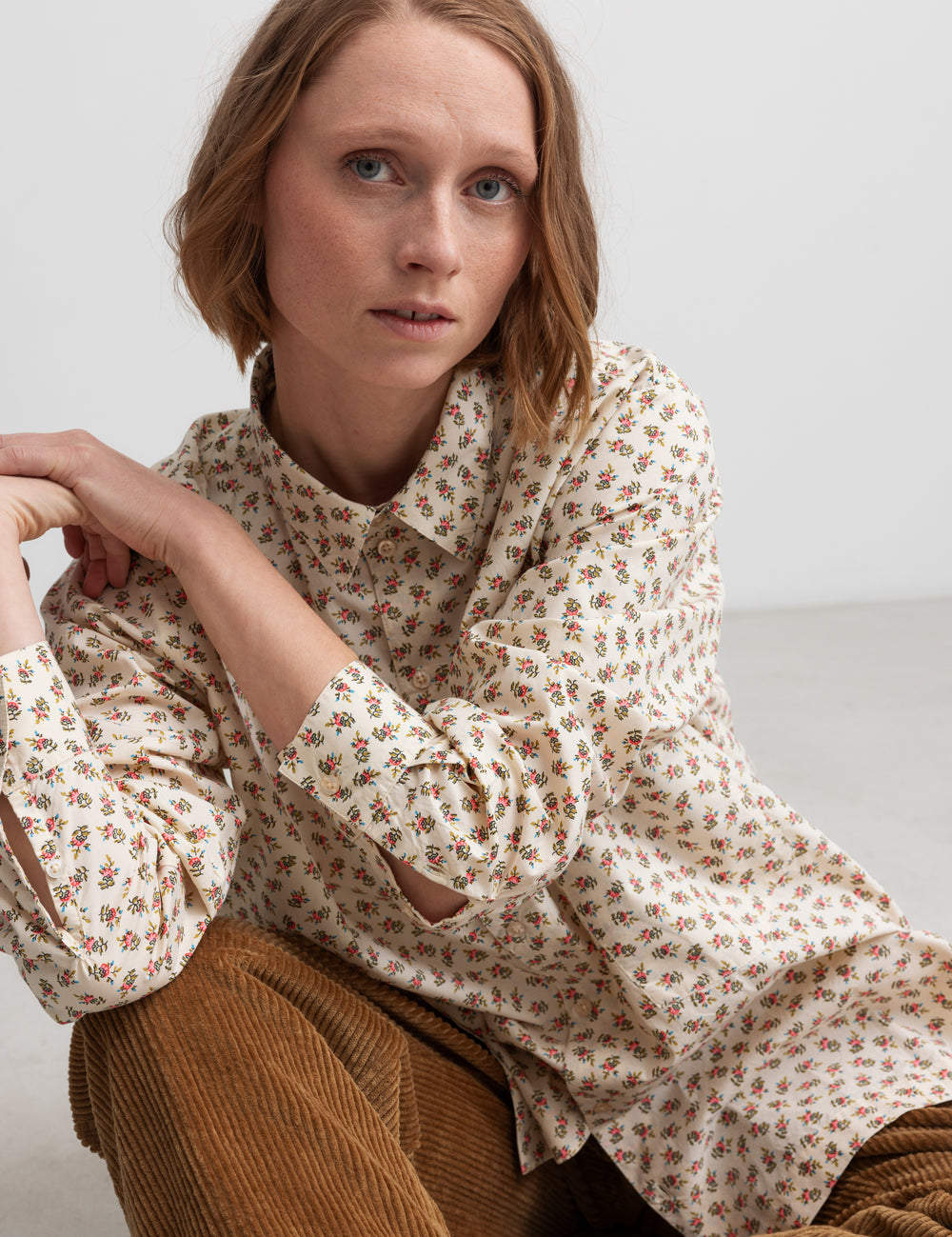 Kvinde iført brune fløjlsbukser og mønstret bluse