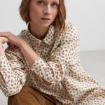 Kvinde iført brune fløjlsbukser og mønstret bluse