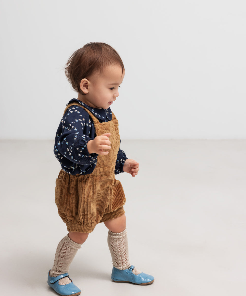 Baby iført mørkeblå blomstermønstret bluse og seleshorts