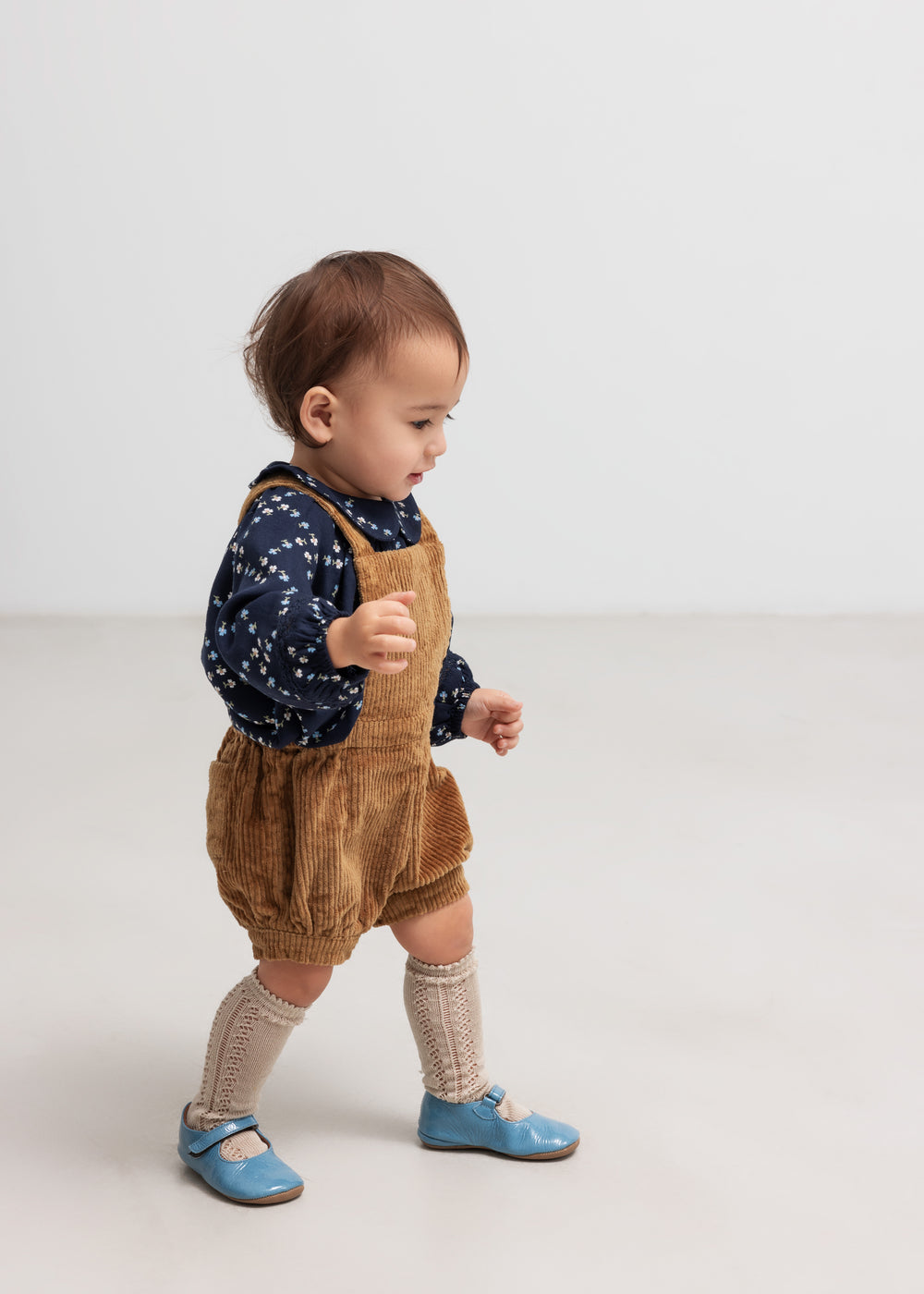 Baby iført mørkeblå blomstermønstret bluse og seleshorts