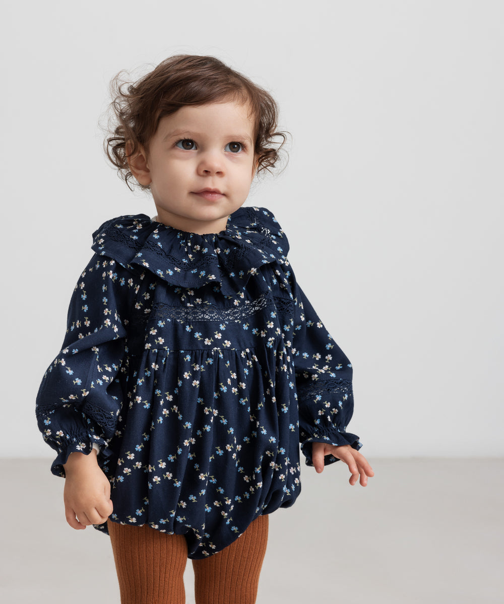 Baby iført mørkeblå blomstermønstret heldragt