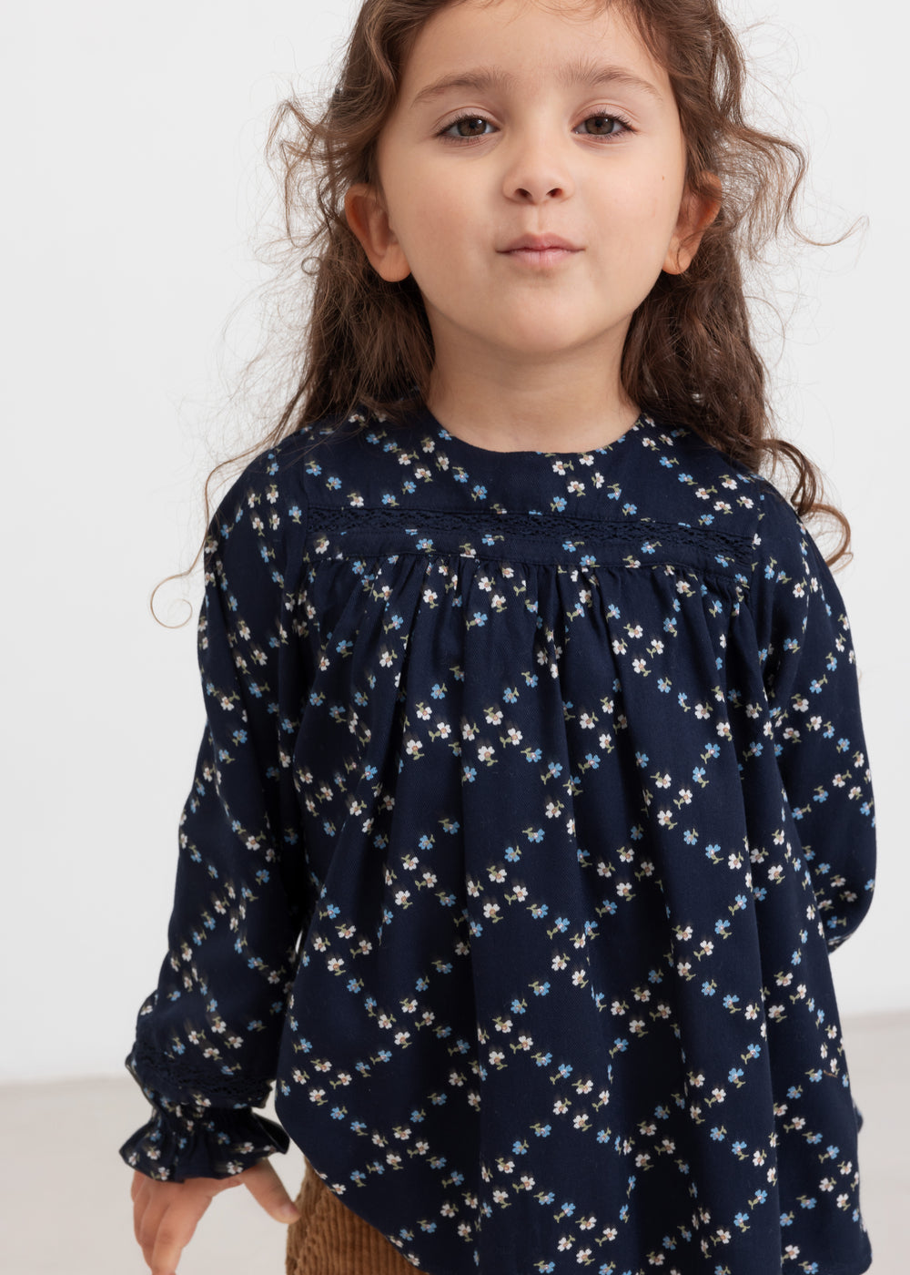 Pige iført mørkeblå blomstermønstret bluse med lange ærmer