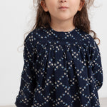 Pige iført mørkeblå blomstermønstret bluse med lange ærmer