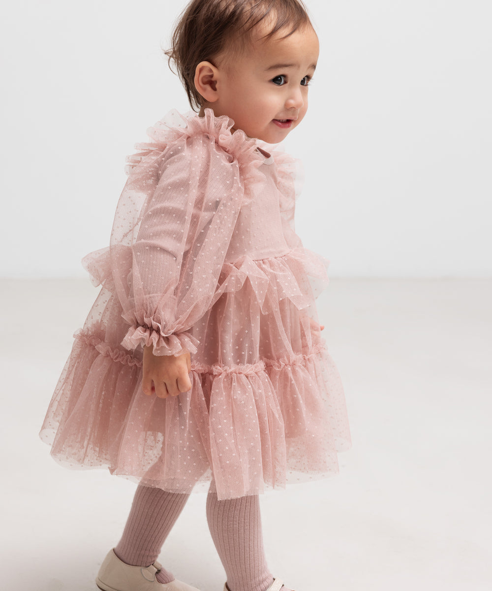 Lille børn i lyserød tylkjole med flæser og lange ærmer