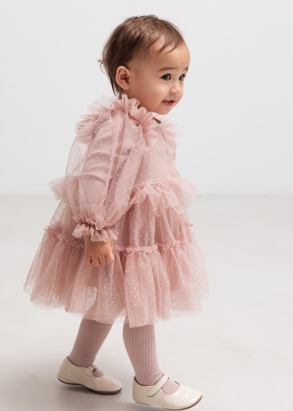 Lille børn i lyserød tylkjole med flæser og lange ærmer