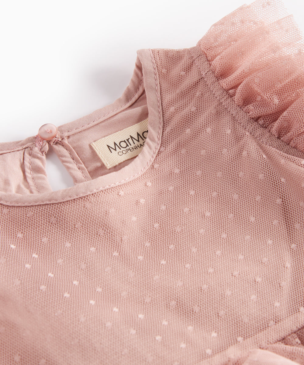 Detaljebillede af lyserød tylkjole med prikmønster og flæser ved halsen