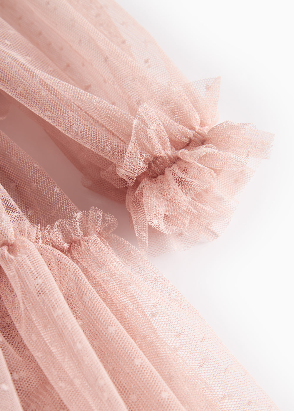 Nærbillede af lyserød tylkjole med elastiske manchetter og flæser