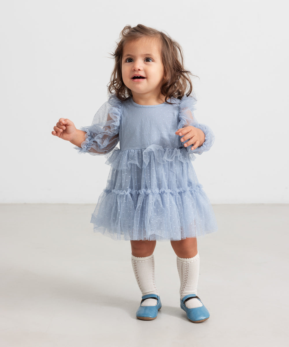 Lille børn i blå tylkjole med flæser og lange ærmer