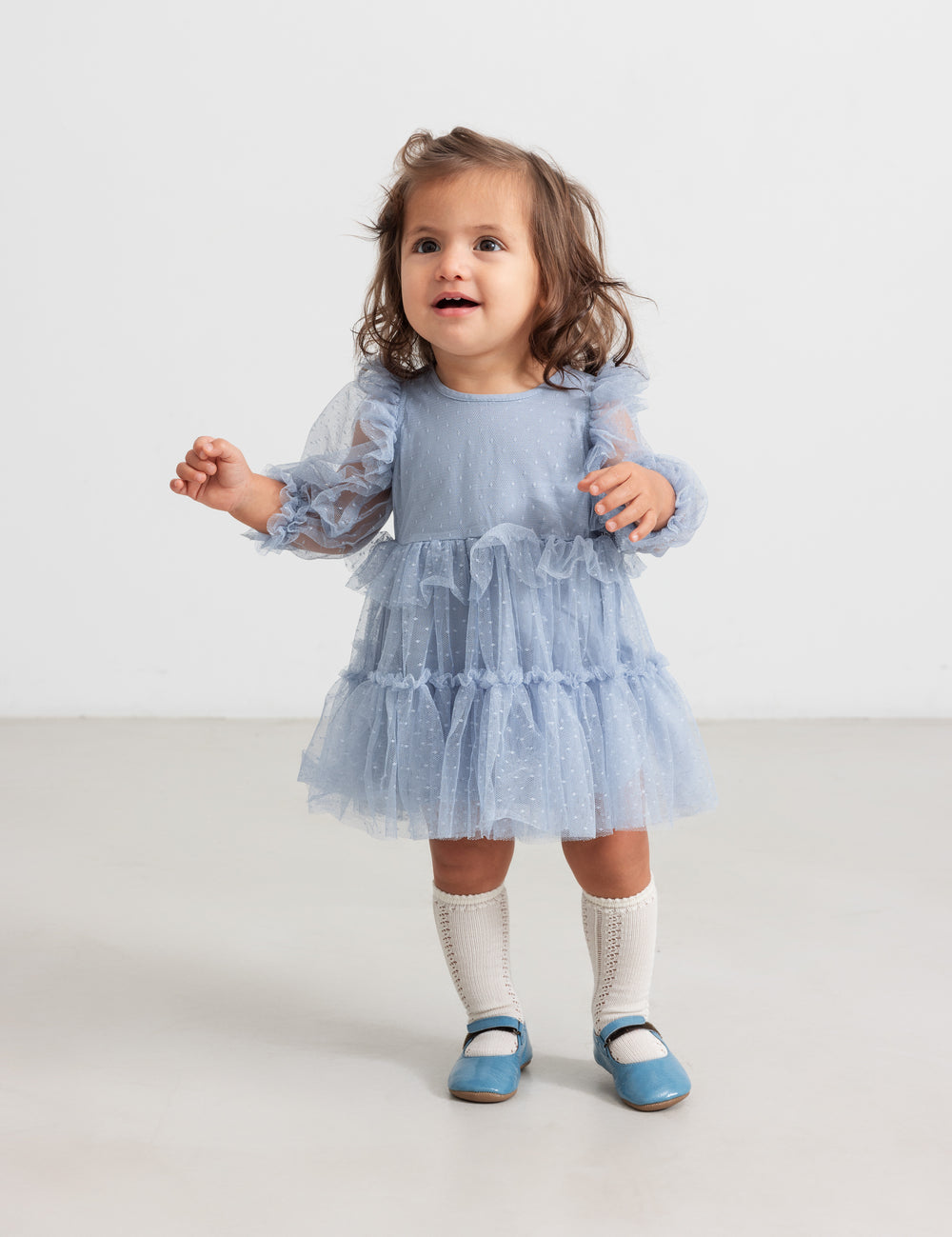 Little child in blue tulle dress with ruffles and long sleeves