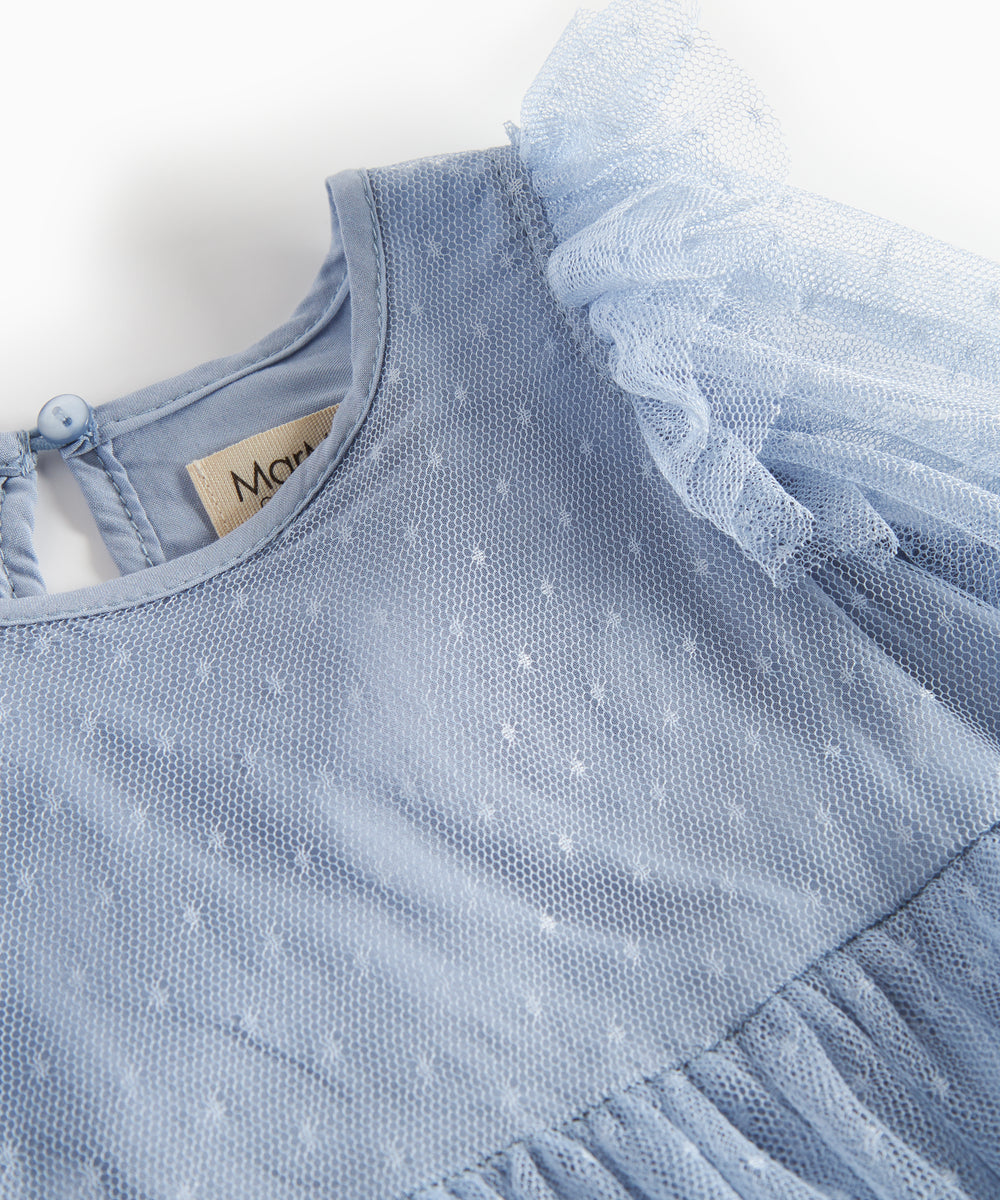 Detaljebillede af blå tylkjole med prikmønster og flæser på skuldrene