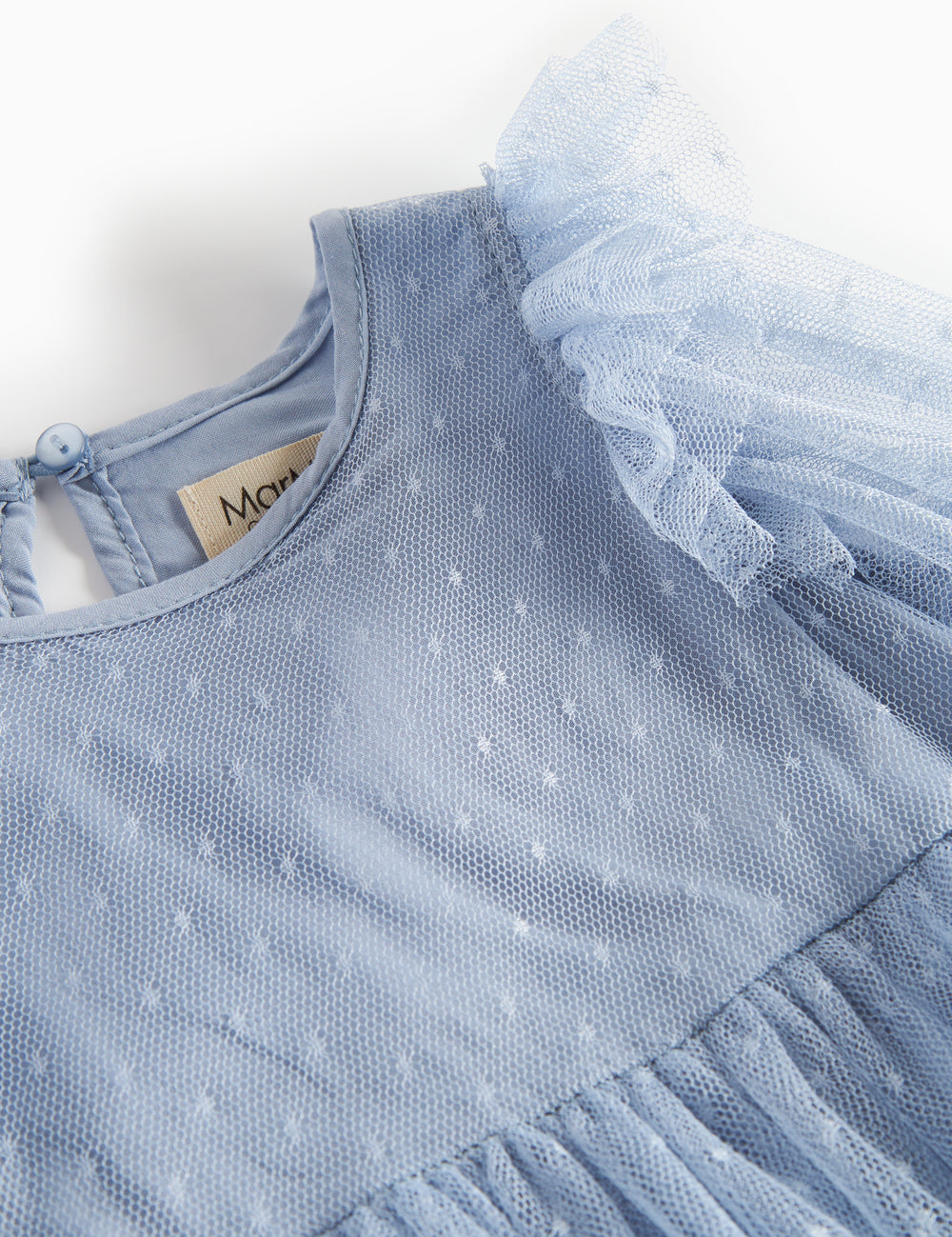 Detail of blue tulle dress with polka dot pattern and ruffles on the shoulders