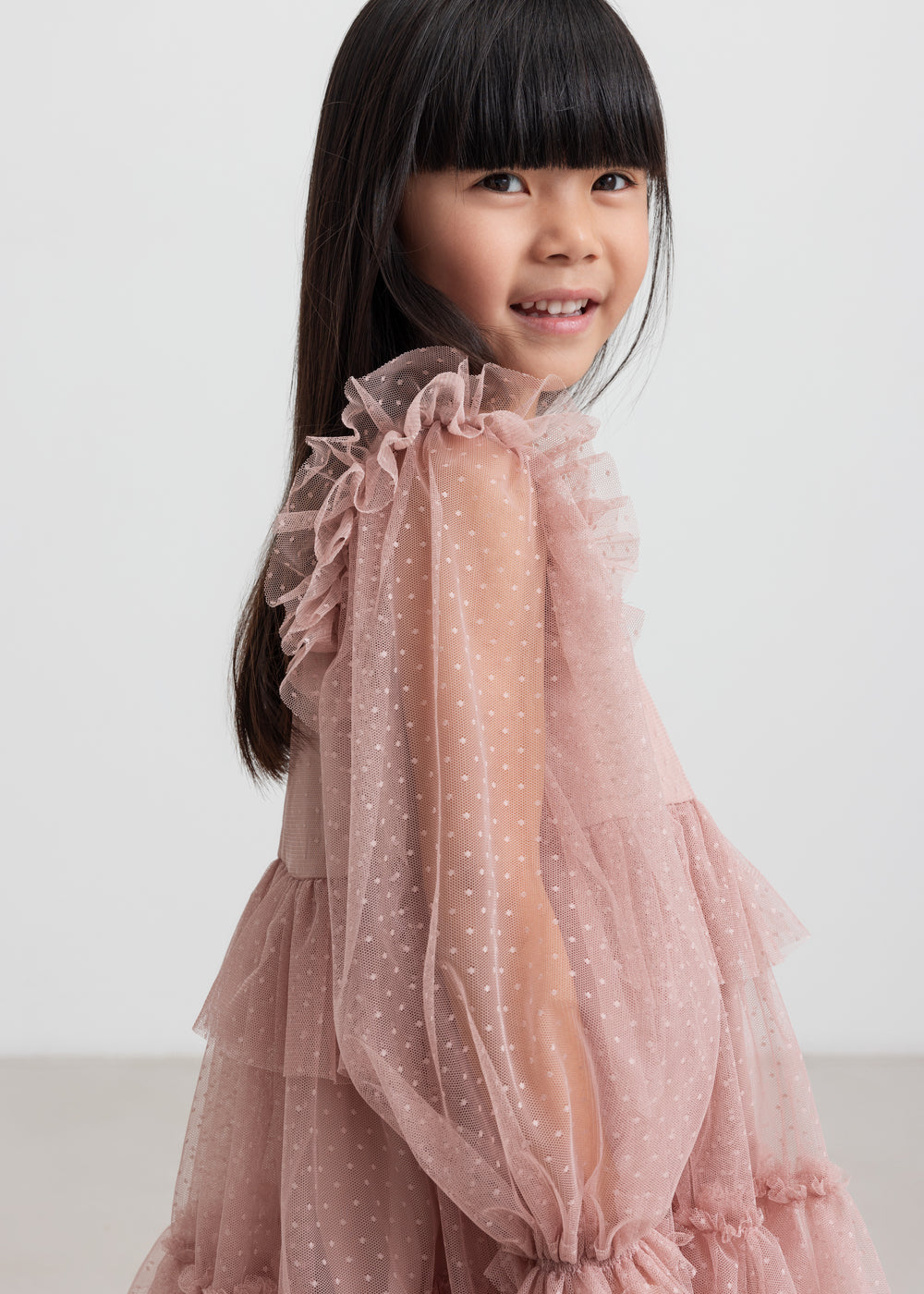 Børn iført rosa tylkjole med volanger på ærmerne