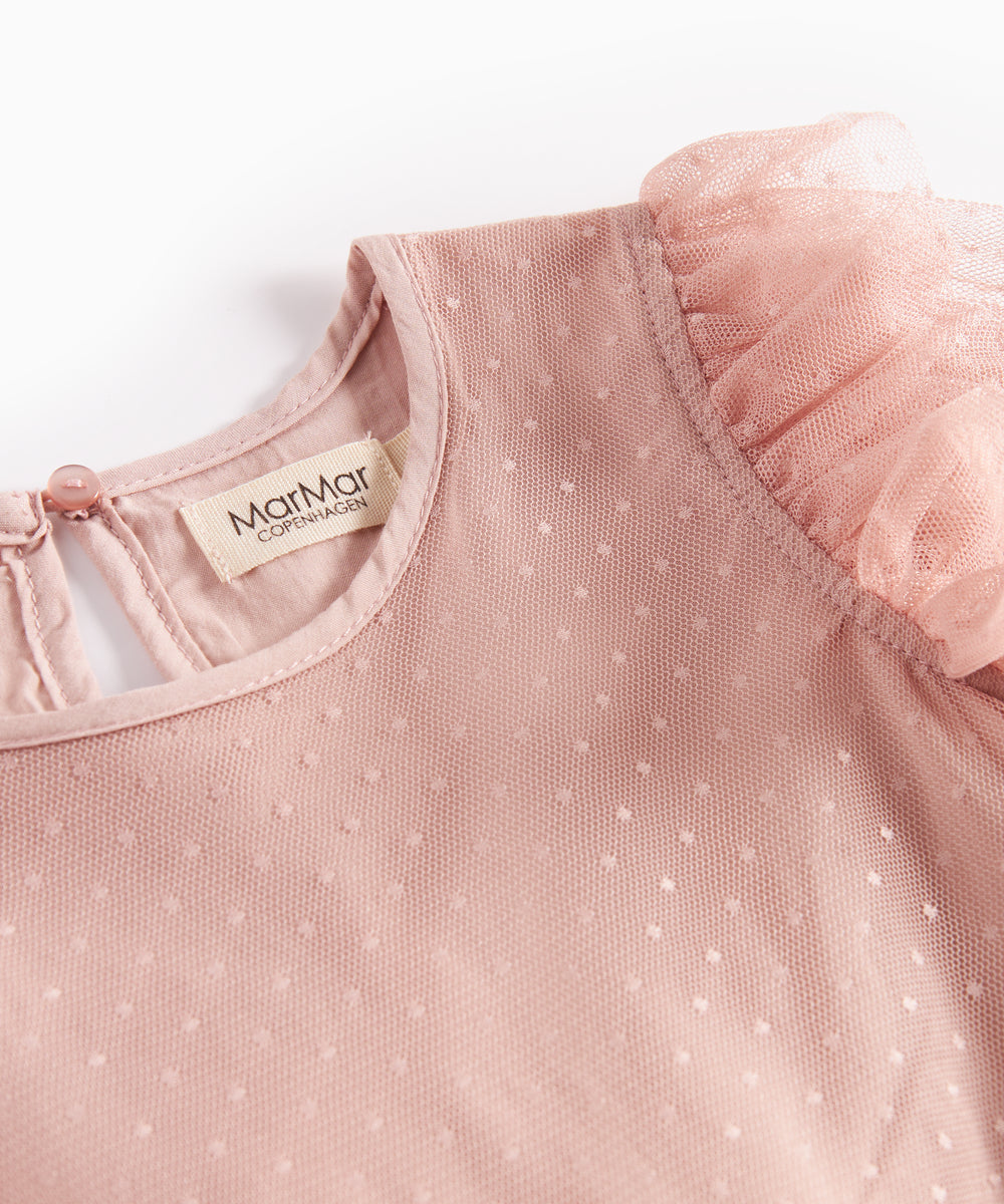 Nærbillede af rosa tylkjole med fint prikmønster og flæsekant på skuldrene