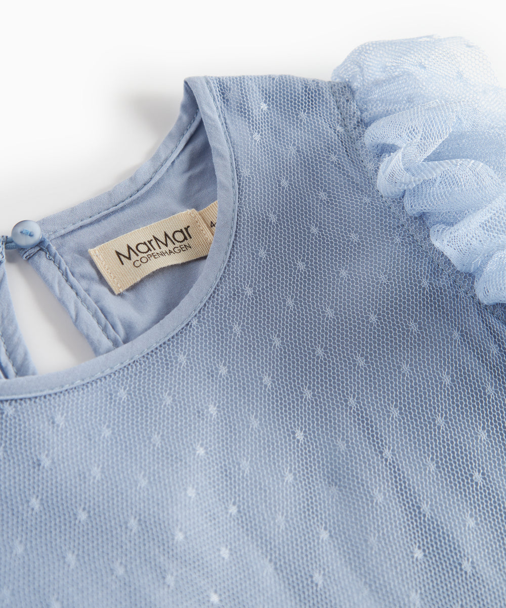 Detaljebillede af blå tylkjole med fint prikmønster og rund hals