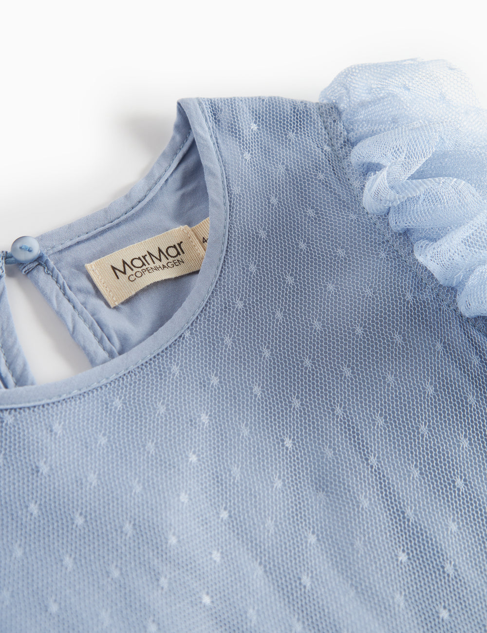 Detaljebillede af blå tylkjole med fint prikmønster og rund hals