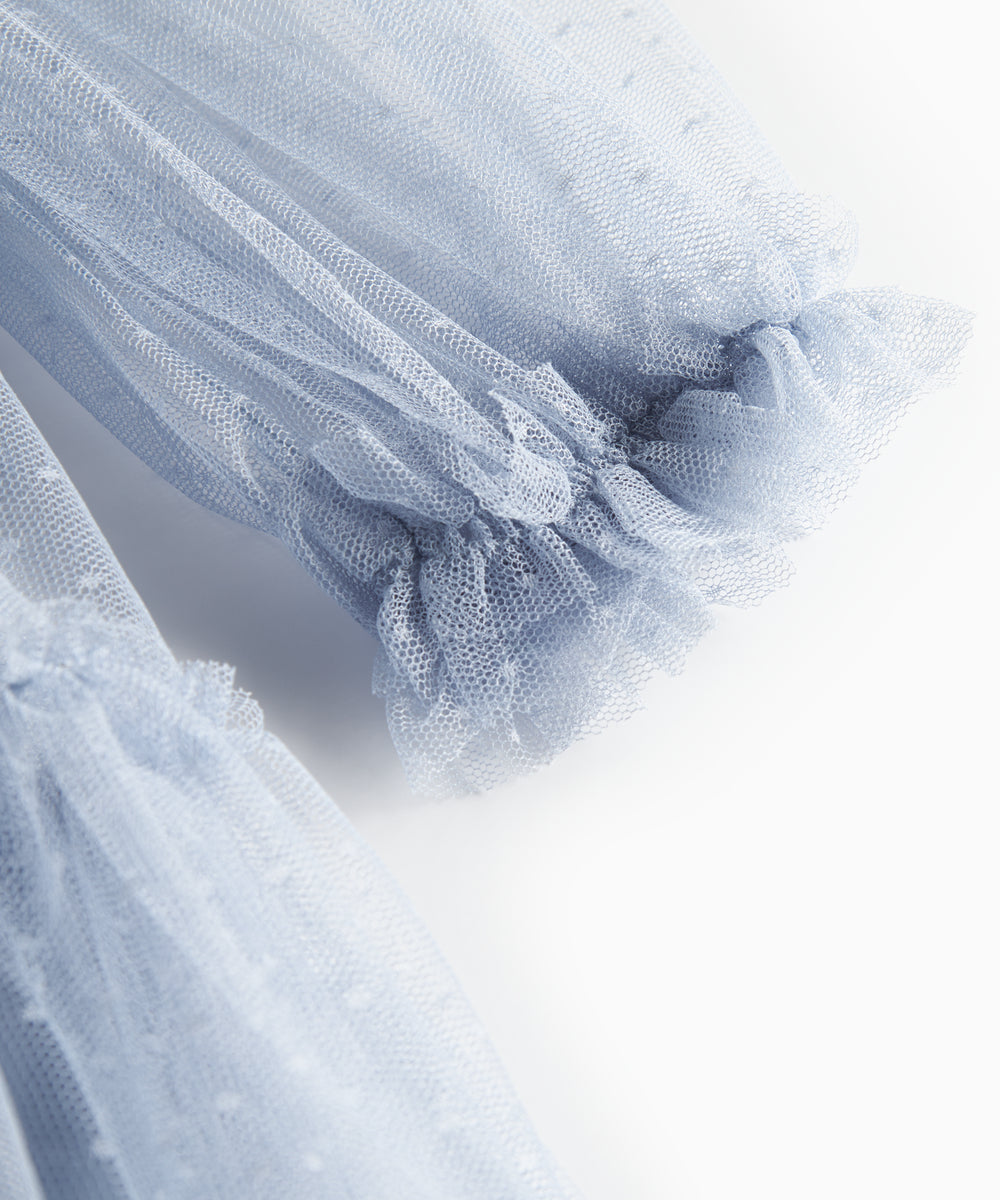 Nærbillede af blå tylkjole med volanger på ærmerne