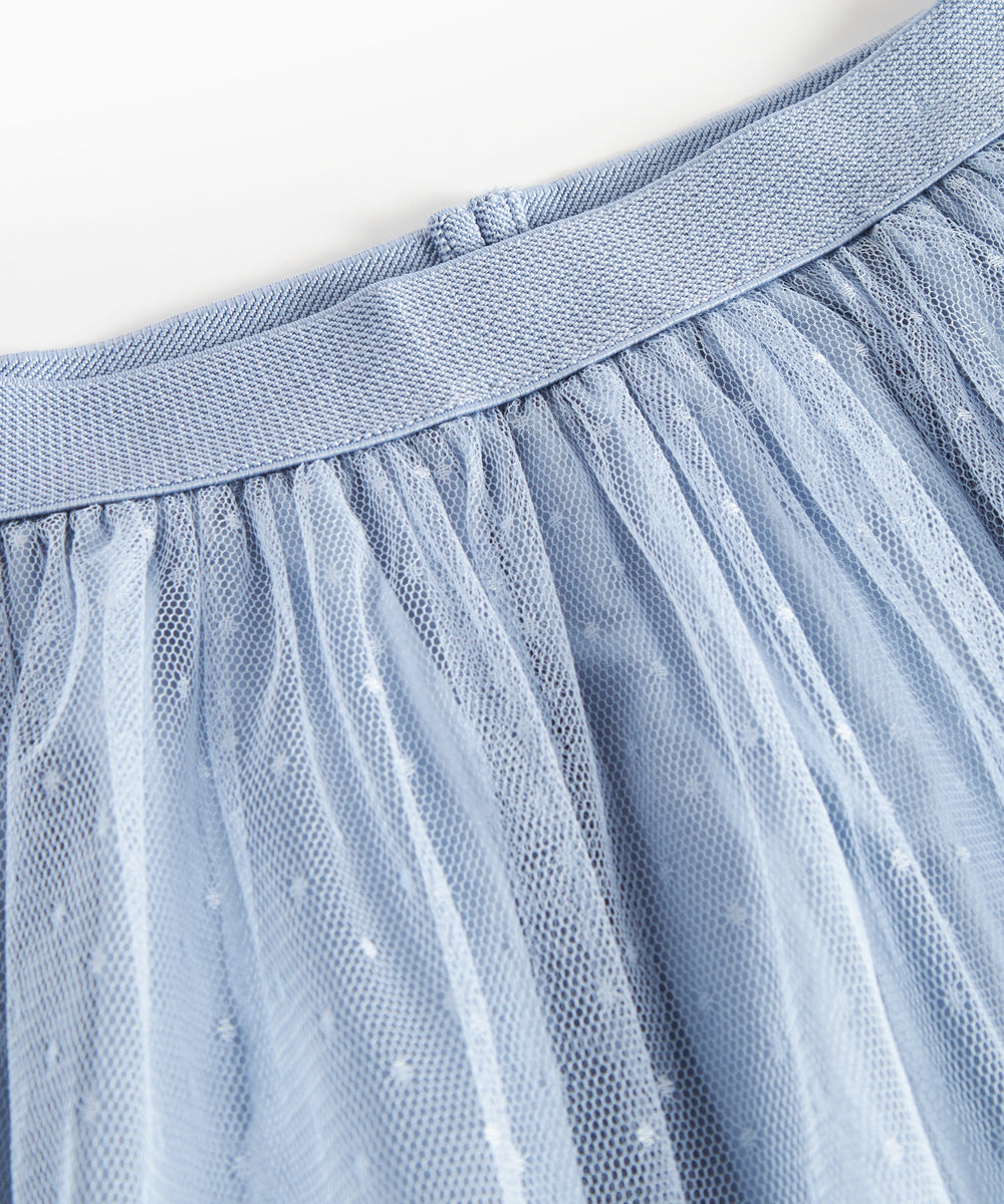 Detaljebillede af blå tylnederdel med prikmønster og elastik i taljen