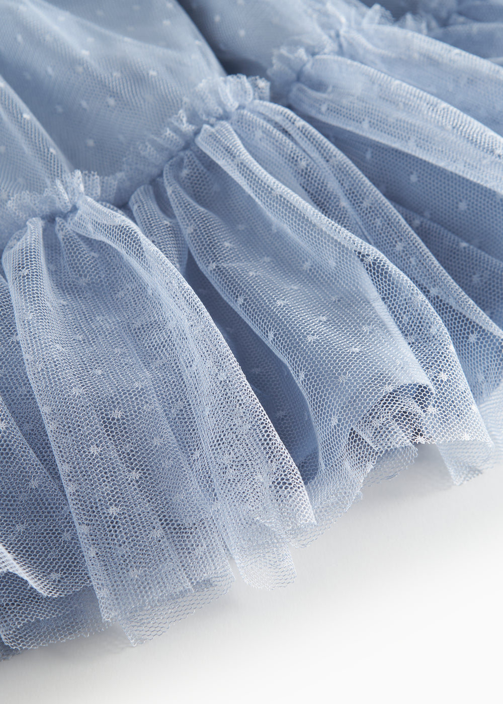 Detaljebillede af blå tylnederdel med prikmønster og elastik i taljen