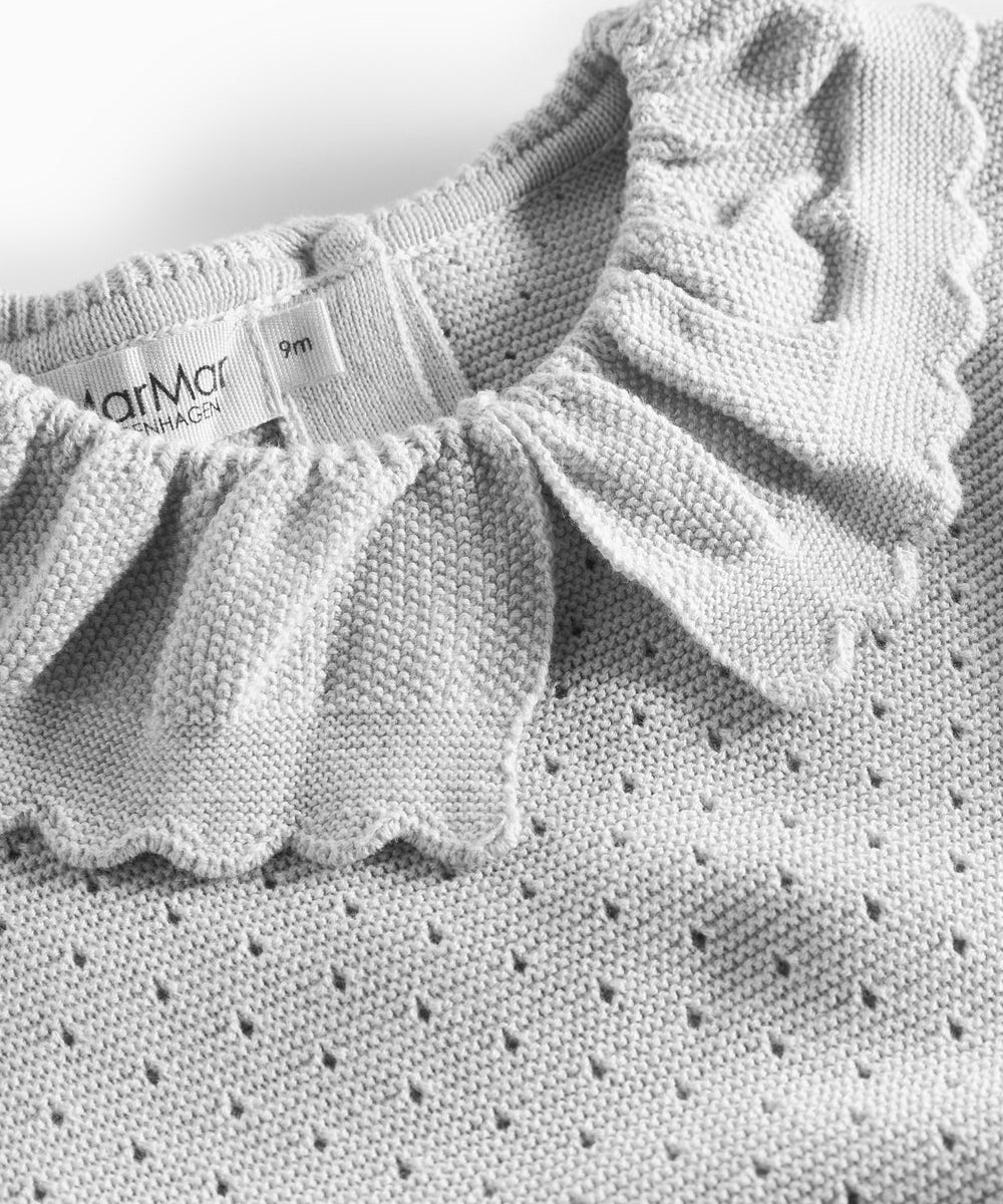 Detalje af flæsekrave på grå strikbluse med hulmønster