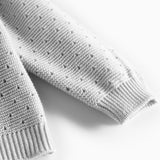 Detalje af ærme med hulmønster på grå strikbluse