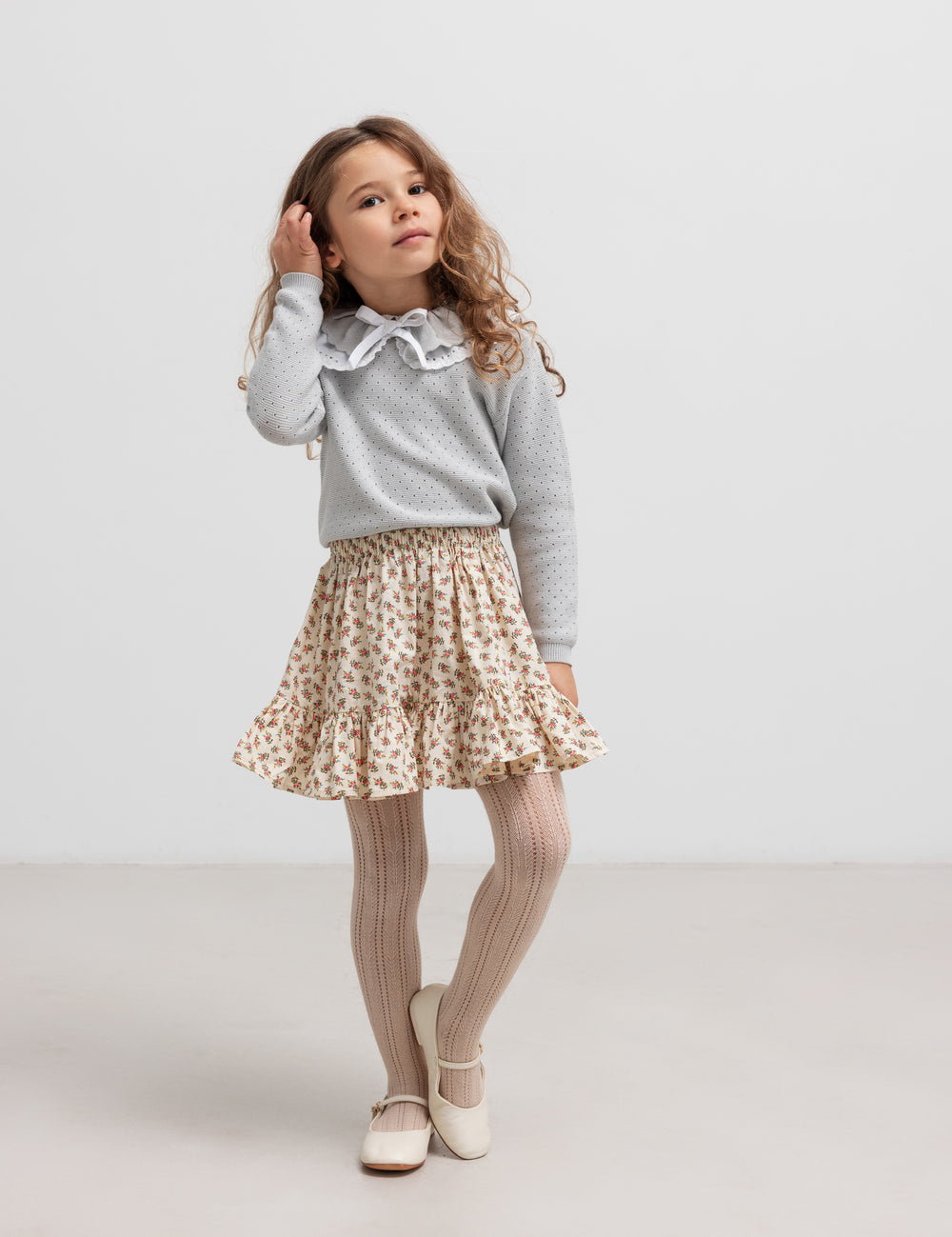 Girl wearing gray knit blouse and skirt, standing and looking away