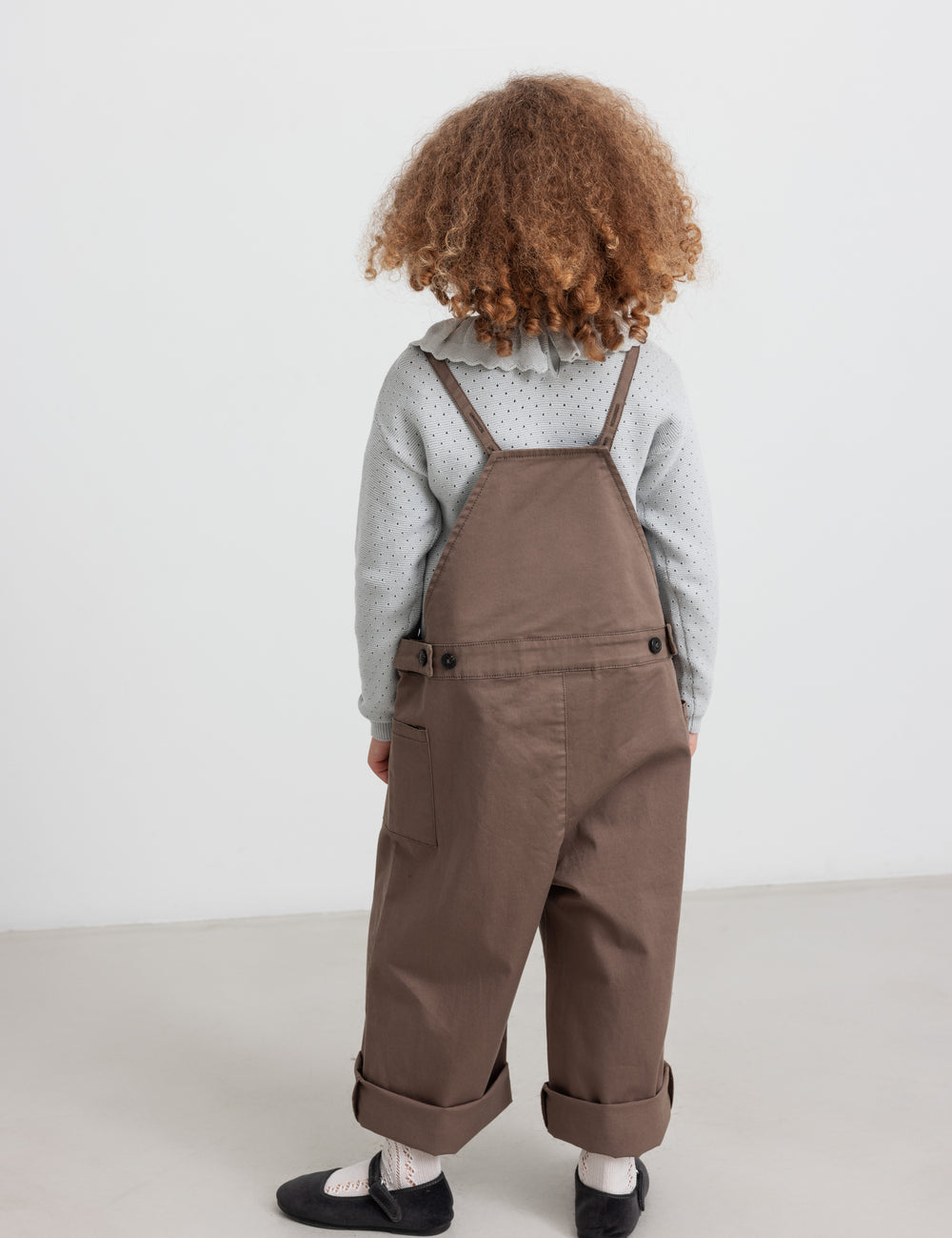 Children wearing khaki suspenders and knitted blouses