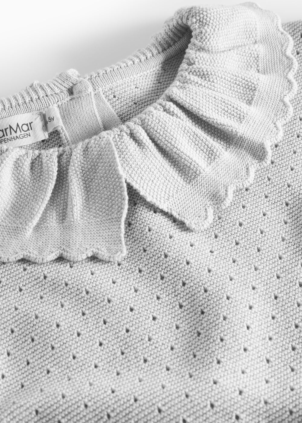 Detalje af flæsekrave på grå strikbluse med hulmønster