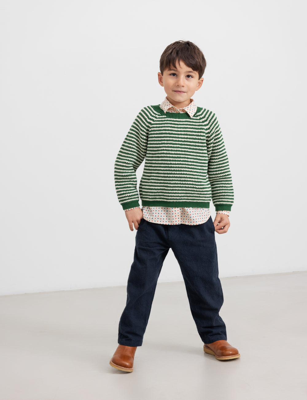 Boy in green striped sweater and jeans, front view