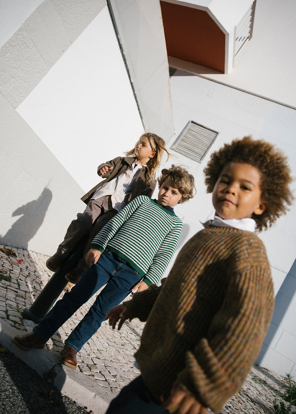 Gruppe børn står ved hvid bygning iført efterårstøj
