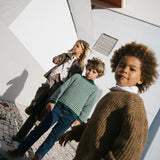 Gruppe børn står ved hvid bygning iført efterårstøj