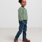 Dreng i grøn stribet striktrøje og jeans set fra siden