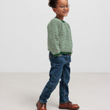 Dreng i grøn stribet striktrøje og jeans set fra siden