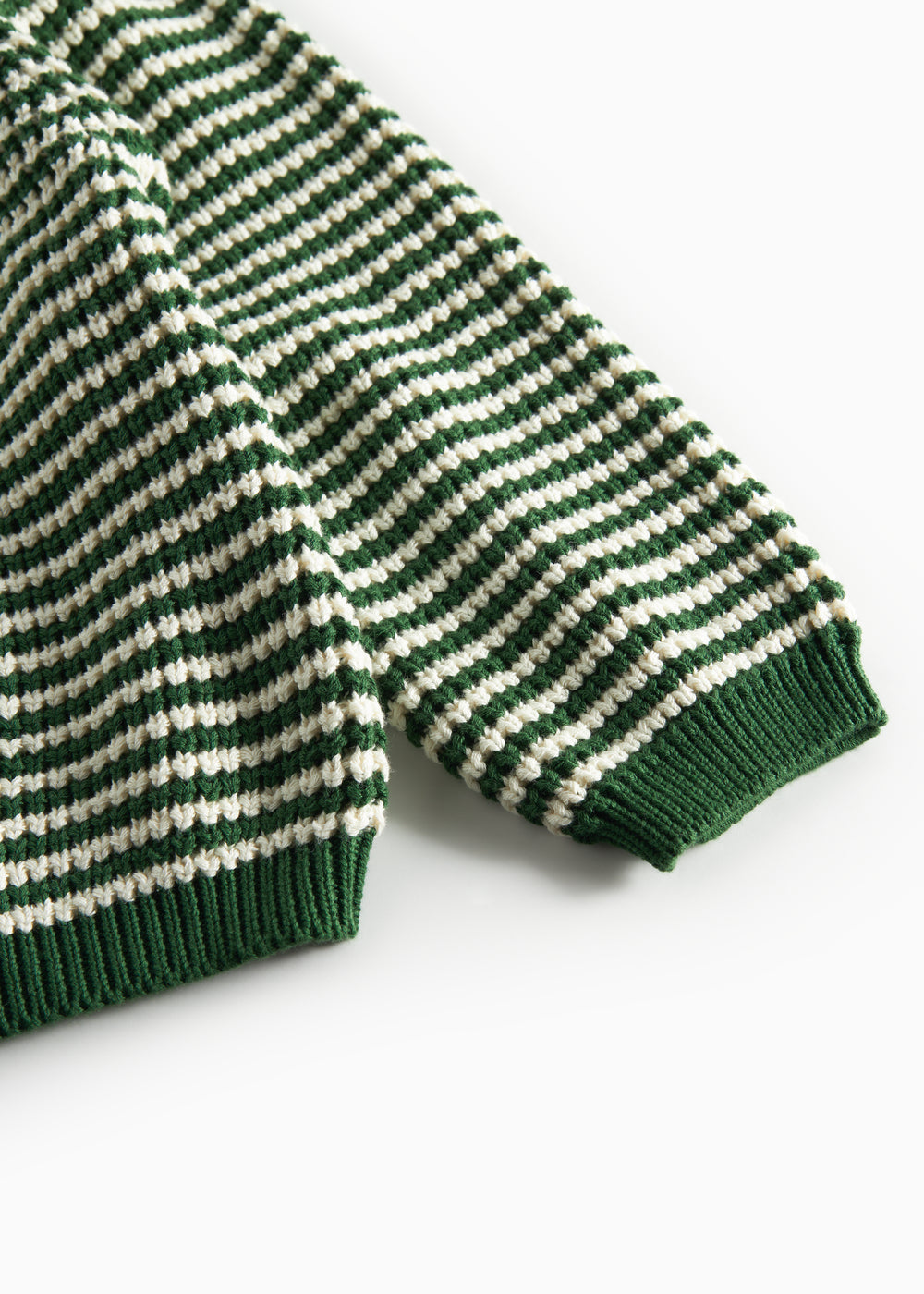 Detaljebillede af ærme på grøn og hvid stribet striktrøje