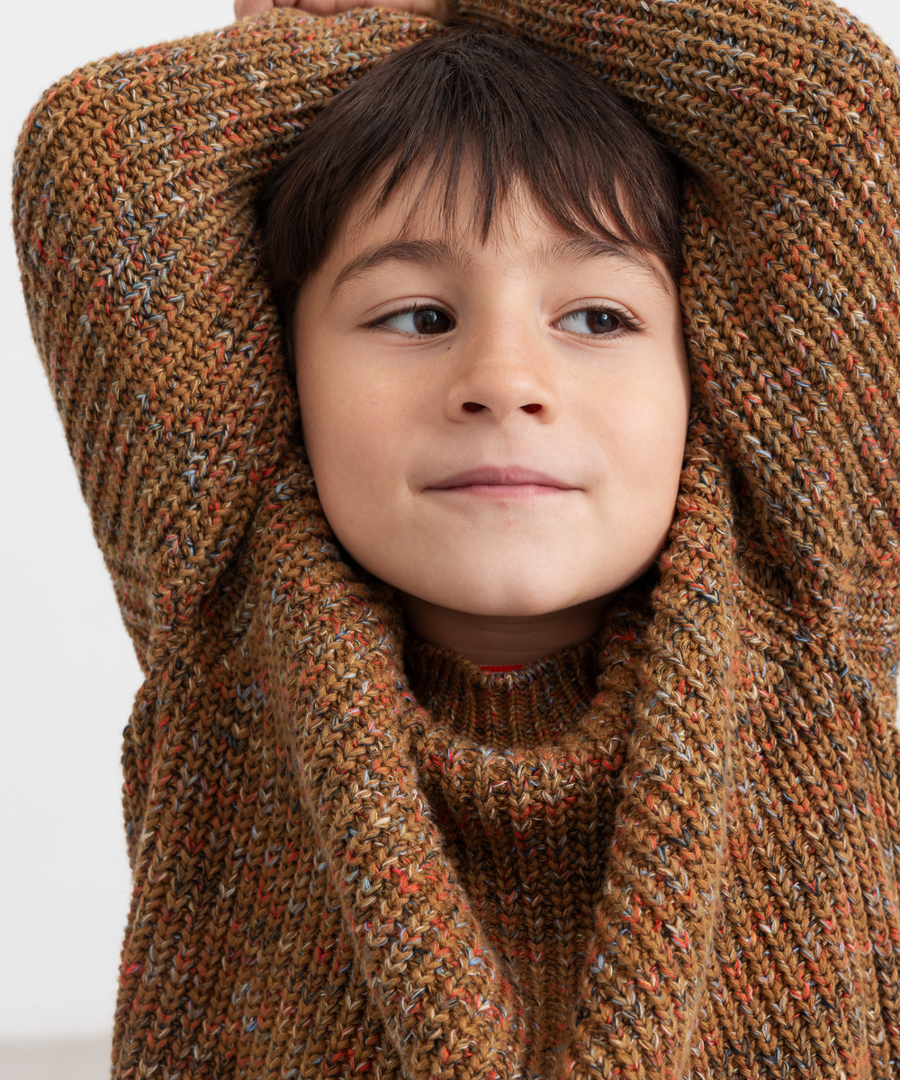 Dreng med brunmeleret striktrøje og hænder bag hovedet