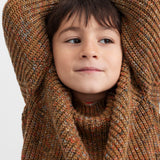 Dreng med brunmeleret striktrøje og hænder bag hovedet