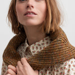 Kvinde iført brunmeleret striktrøje og blomstret skjorte