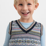 Dreng iført mønstret strikvest over lyseblå bluse