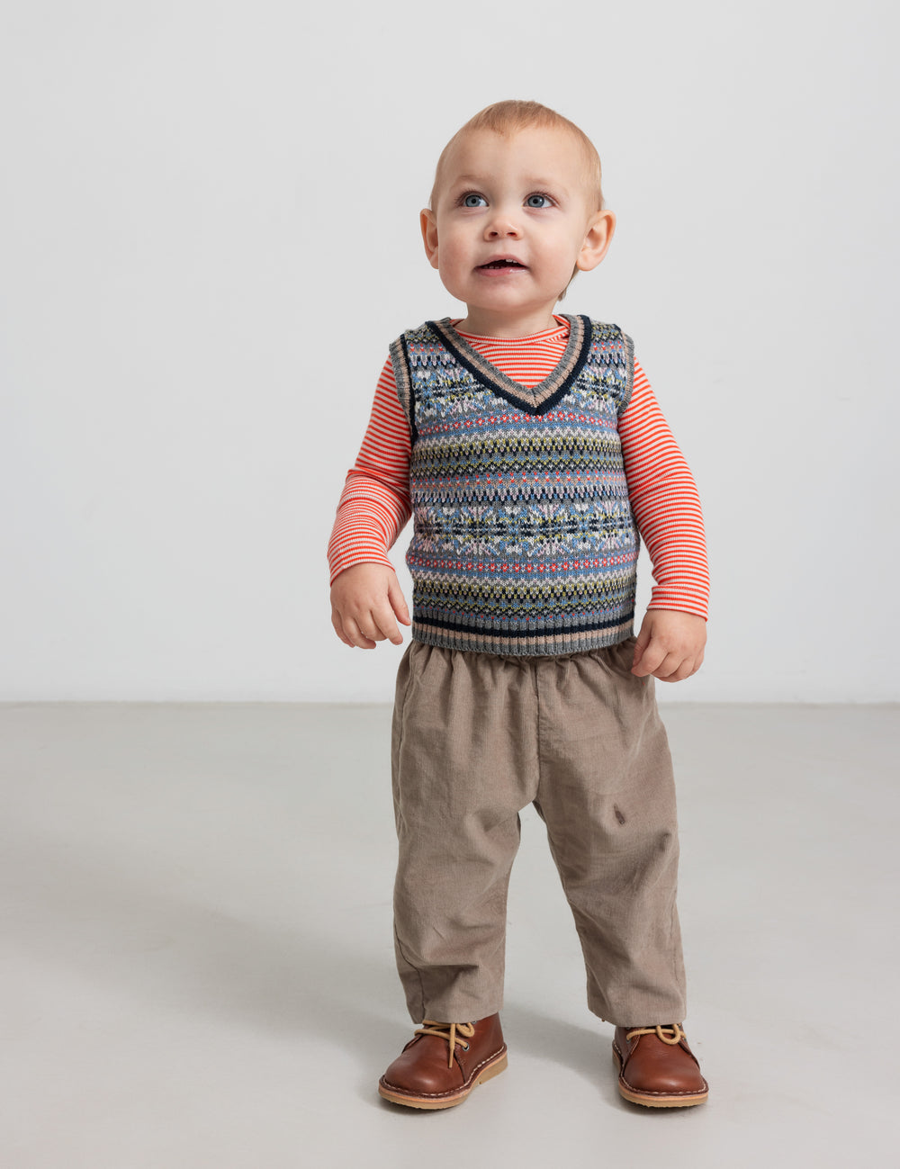 Baby wearing patterned knit vest over striped blouse