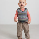 Baby iført mønstret strikvest over stribet bluse