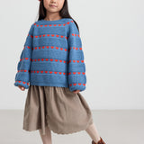 Børn i blå strikbluse og rød beret med kvast