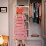 Børn foran garderobe iført rødstribet kjole og matchende beret