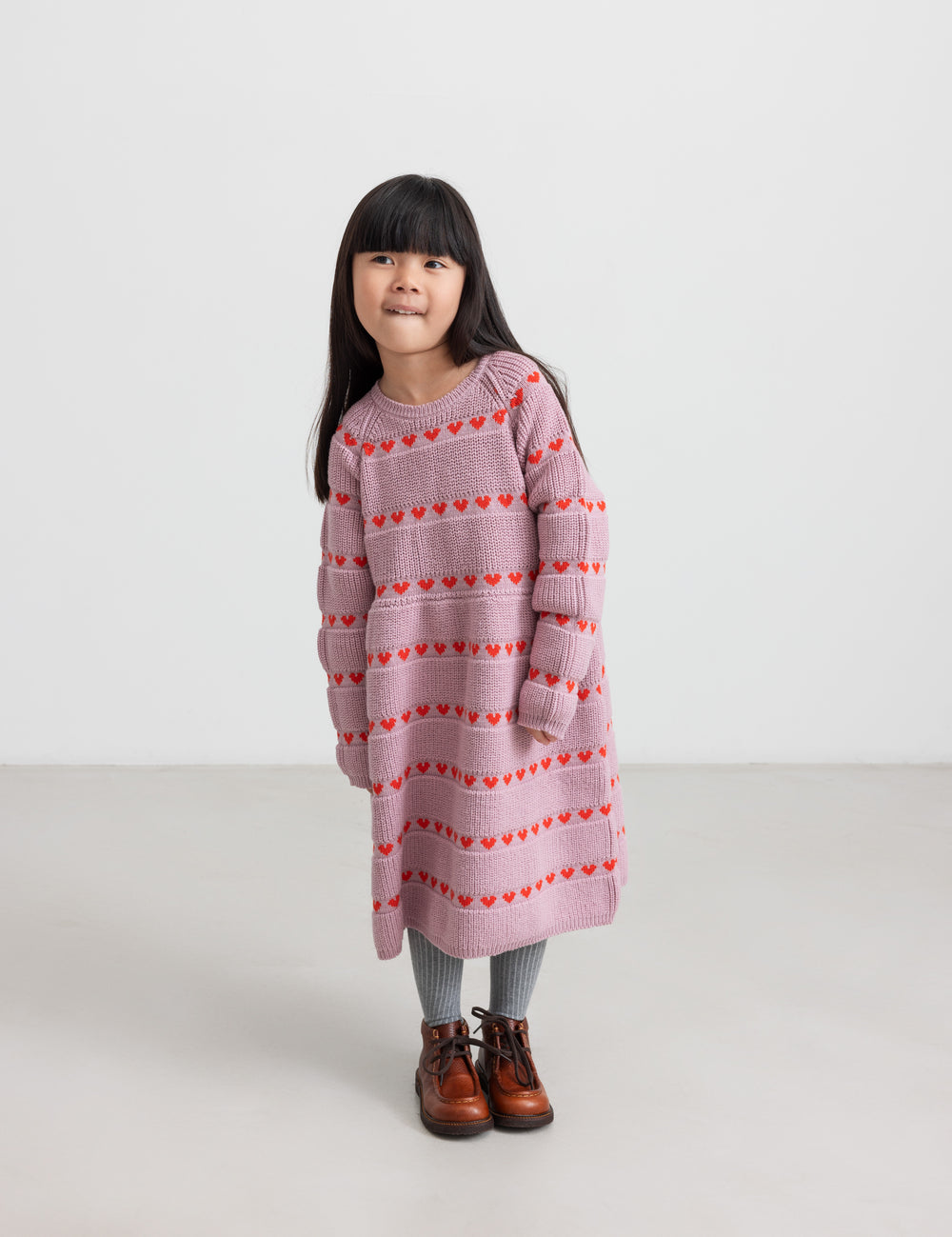 Pige iført lyserød strikkjole med røde hjerter