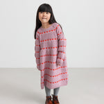 Pige iført lyserød strikkjole med røde hjerter