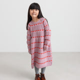 Pige iført lyserød strikkjole med røde hjerter