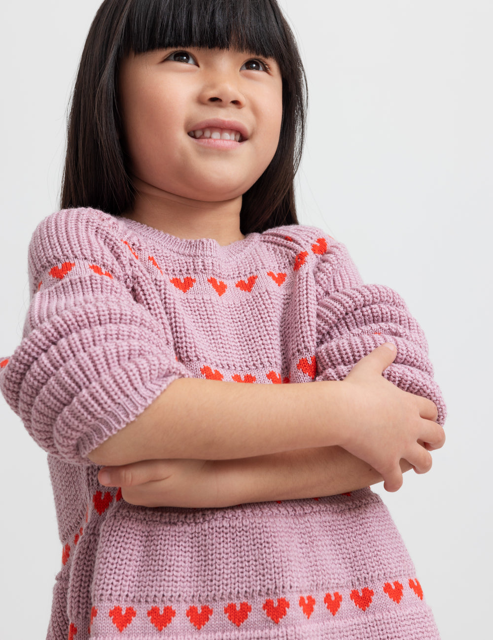 Pige iført lyserød strikkjole med røde hjerter