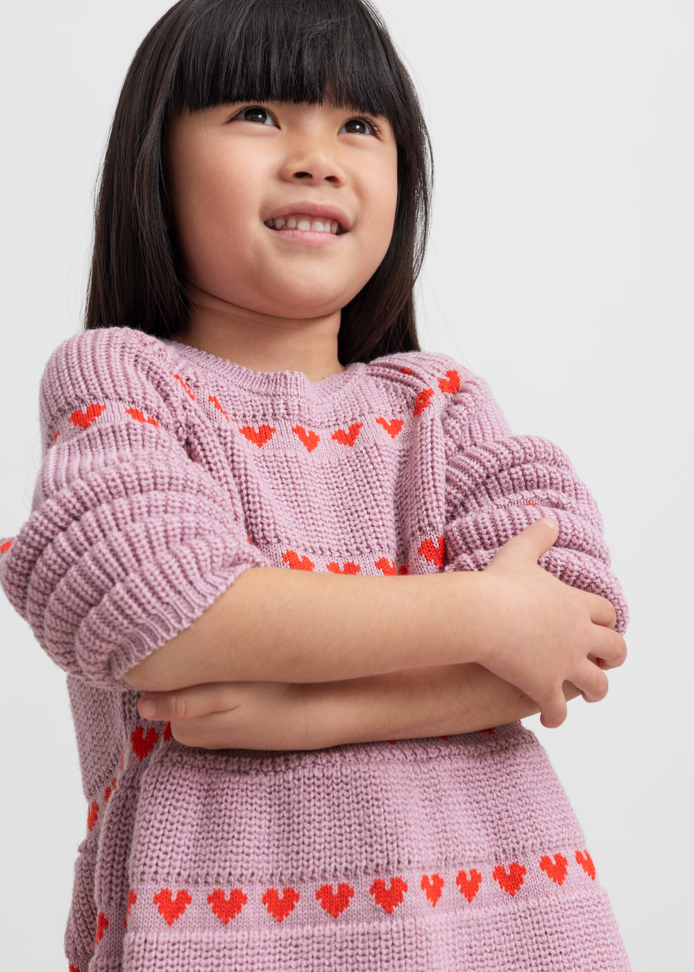Pige iført lyserød strikkjole med røde hjerter